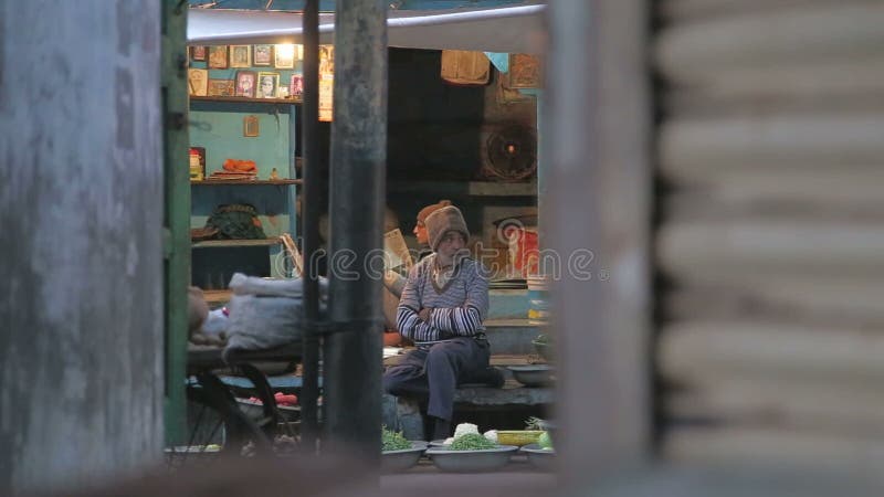 Portrait d'un homme plus âgé se reposant à la rue avec ses marchandises tandis que les gens passent par