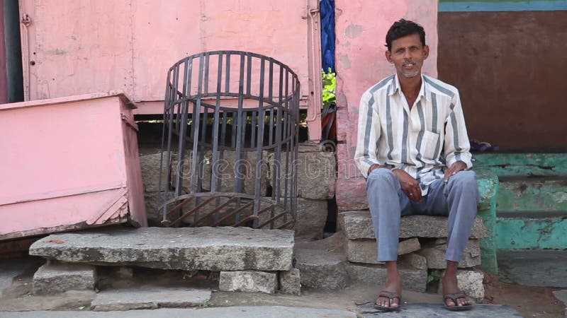 Portrait d'un homme s'asseyant devant la maison rose dans Hampi