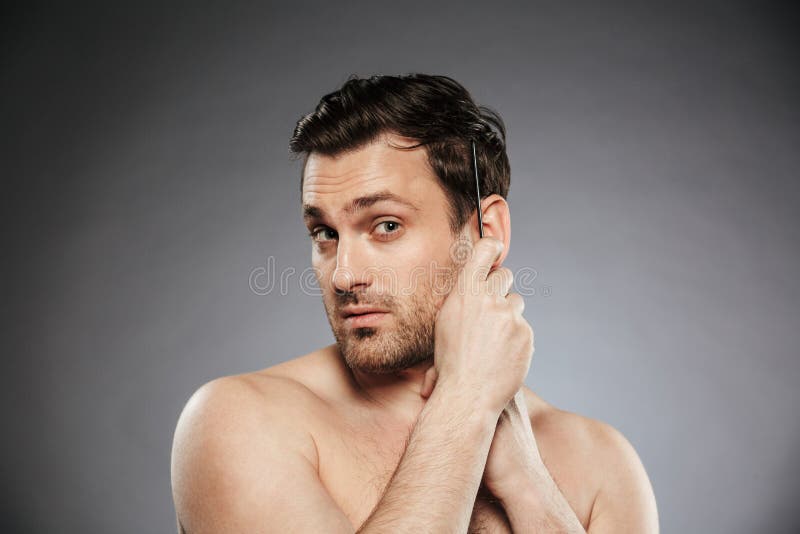Portrait d'un homme sans chemise sûr se peignant les cheveux image stock Portrait d'un homme sans chemise sûr se peignant les cheveux image stock