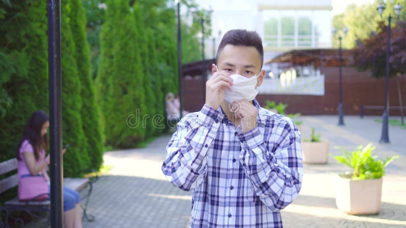 Portrait d'un jeune homme asiatique portant un masque mÃ©dical dans la rue du parc