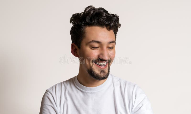 Portrait d'un jeune homme avec le sourire d'accolades Un jeune homme heureux avec des accolades sur un fond blanc images libres de droits Portrait d'un jeune homme avec le sourire d'accolades Un jeune homme heureux avec des accolades sur un fond blanc images libres de droits