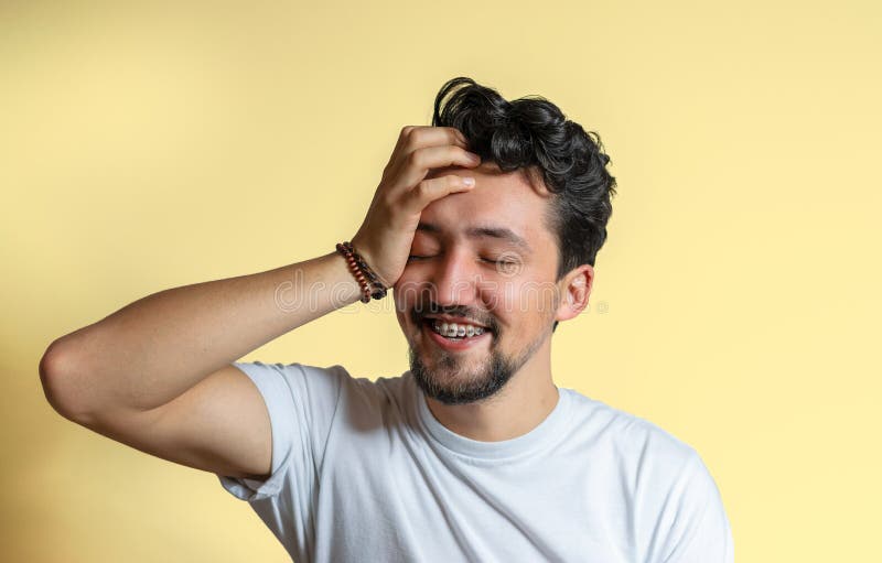 Portrait d'un jeune homme avec le sourire d'accolades Un jeune homme heureux avec des accolades sur un fond jaune images stock Portrait d'un jeune homme avec le sourire d'accolades Un jeune homme heureux avec des accolades sur un fond jaune images stock
