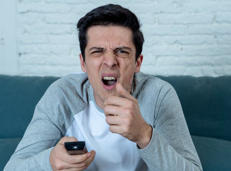 Portrait d'un jeune homme semblant TV de observation effrayée et choquée Expressions et photo libre de droits Portrait d'un jeune homme semblant TV de observation effrayée et choquée Expressions et photo libre de droits