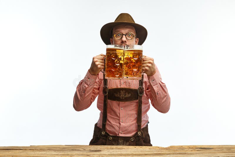 Exciting. Portrait of young emotional man in hat, wearing traditional Bavarian clothes, holding beer mug isolated white background. Alcohol, traditions, holidays, festival and ad concept. Exciting. Portrait of young emotional man in hat, wearing traditional Bavarian clothes, holding beer mug isolated white background. Alcohol, traditions, holidays, festival and ad concept.