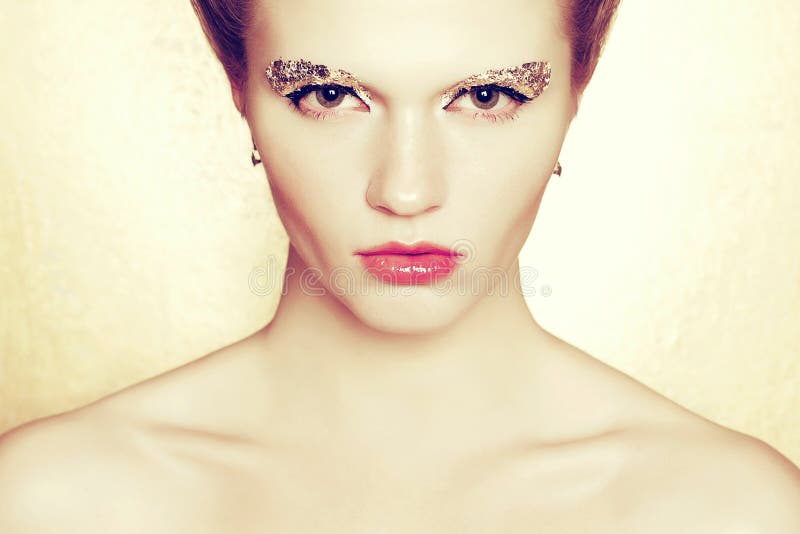 Portrait d'un modèle à la mode avec le maquillage de style bohème de l'aluminium d'or posant au-dessus du fond d'or Type de mode photos libres de droits Portrait d'un modèle à la mode avec le maquillage de style bohème de l'aluminium d'or posant au-dessus du fond d'or Type de mode photos libres de droits