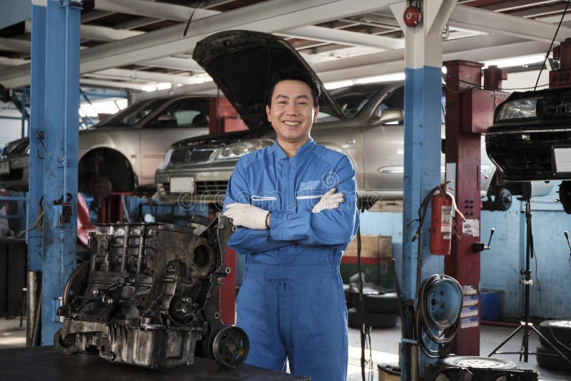 Portrait d'un mécanicien asiatique en uniforme dans un garage de service de voiture. photo stock