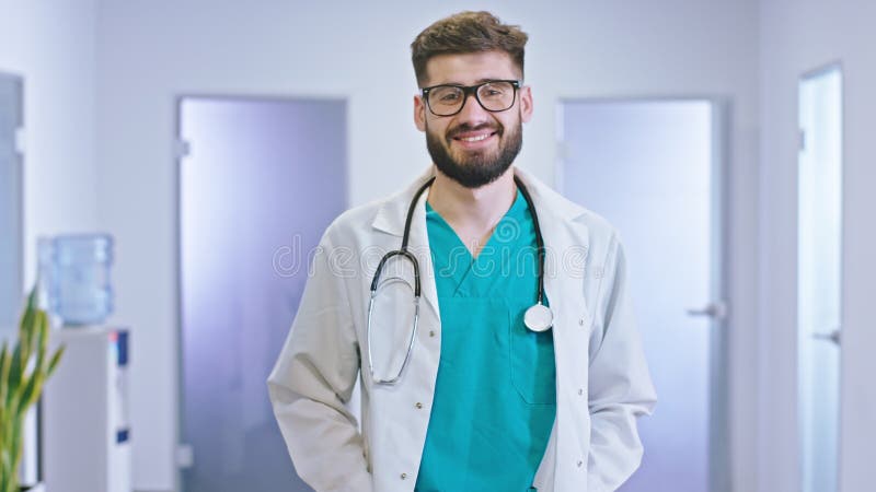 Portrait d'un médecin de jeune homme dans le couloir d'hôpital regardant droit au sourire de caméra grand