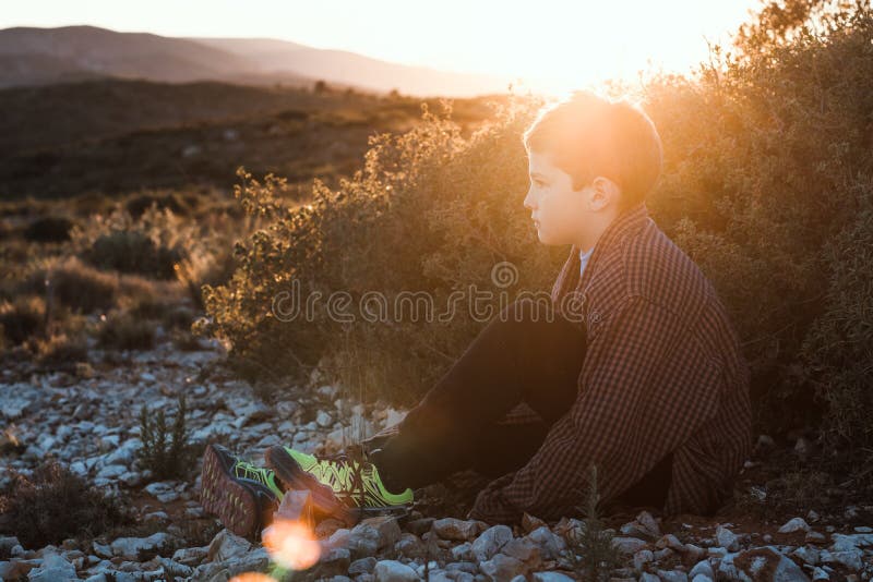 Portrait d'un petit garçon blond s'asseyant dans le domaine Petit garçon beau dans un coucher du soleil photos libres de droits Portrait d'un petit garçon blond s'asseyant dans le domaine Petit garçon beau dans un coucher du soleil photos libres de droits