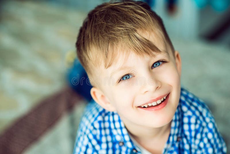 Portrait d'un petit garçon de sourire aux yeux bleus se trouvant sur le lit de ses parents images stock Portrait d'un petit garçon de sourire aux yeux bleus se trouvant sur le lit de ses parents images stock