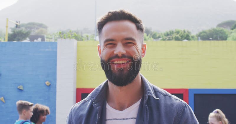 Portrait d'un professeur mâle caucasien heureux avec un groupe diversifié heureux d'enfants en arrière-plan banque de vidéos