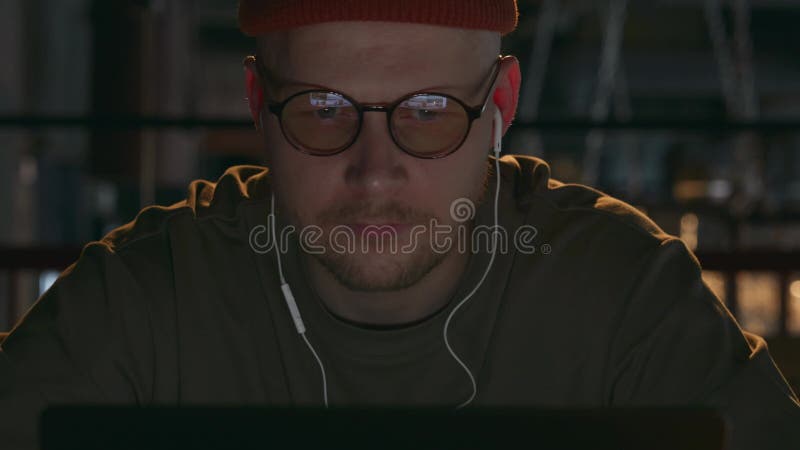 Portrait d'un programmeur informatique travaillant dans un café sombre sur l'ordinateur portable