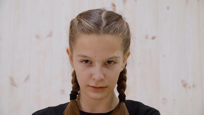 Portrait d'une adolescente sérieuse cherchant un appareil photo dans un studio léger Fermez le visage, une adolescente en colère clips vidéos