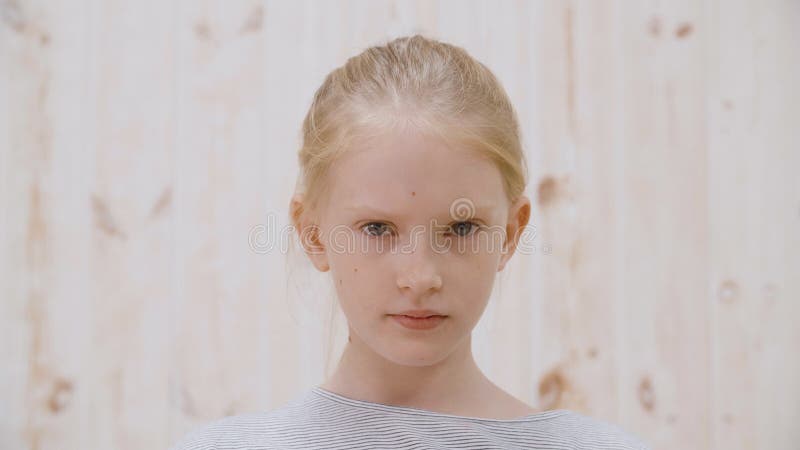 Portrait d'une adolescente sérieuse cherchant un appareil photo sur un mur lumineux en studio Fermez le visage d'une adolescente banque de vidéos