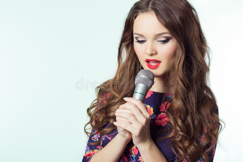Portrait of a beautiful elegant girl singer brunette with long hair with a microphone in his hand singing a song. Portrait of a beautiful elegant girl singer brunette with long hair with a microphone in his hand singing a song