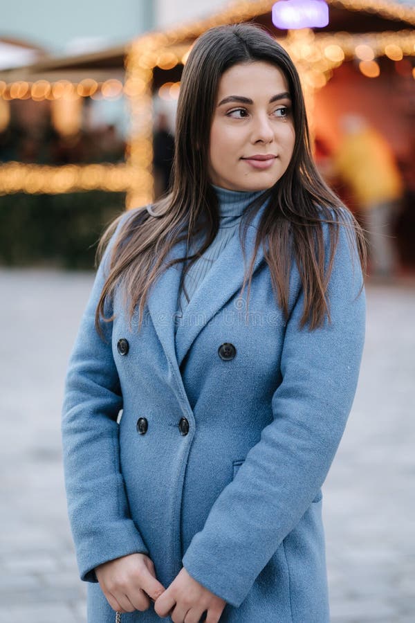 Portrait d'une belle femme heureuse en manteau bleu d'hiver debout devant la lumière de noël dans la vieille ville. humeur hiverna photos stock