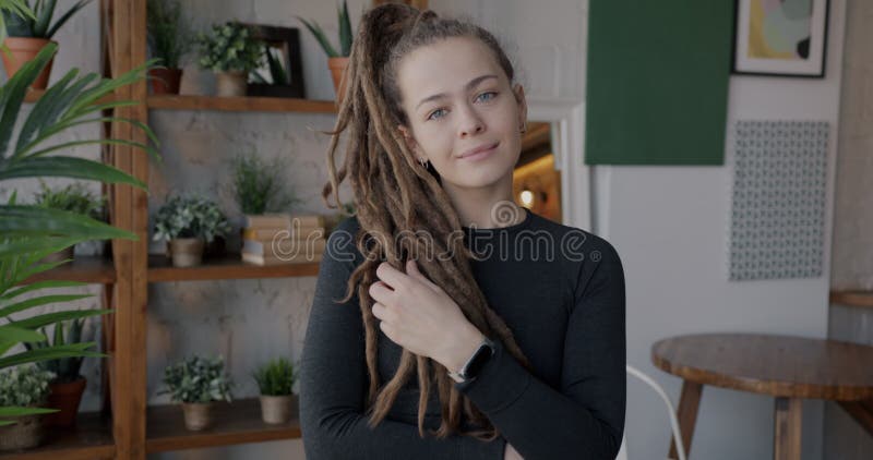 Portrait d'une belle jeune femme avec des poignées créatives coiffure sourire debout dans un appartement moderne banque de vidéos