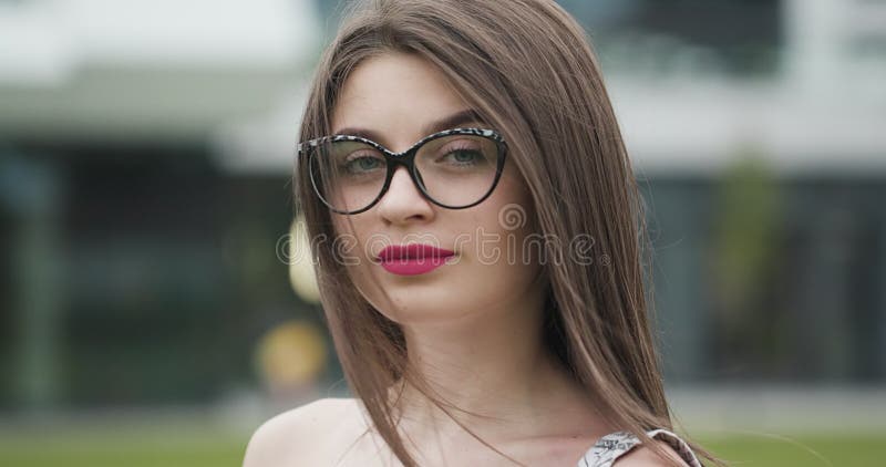 Portrait d'une belle jeune femme en lunettes regardant la caméra à l'extérieur dans la rue de la ville