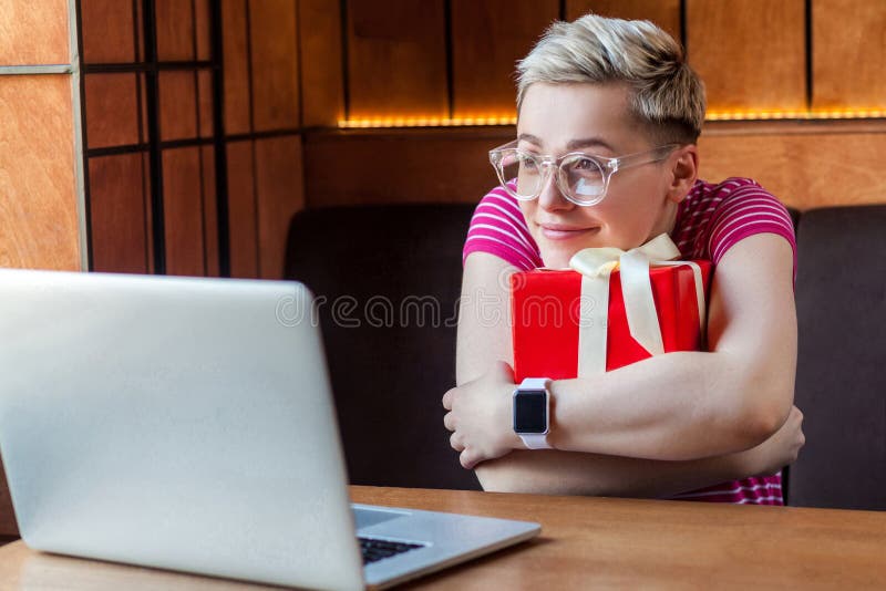 Portrait d'une belle jeune femme heureuse rêveuse et heureuse avec des cheveux courts en t-shirt rose et lunettes est assise dans images stock