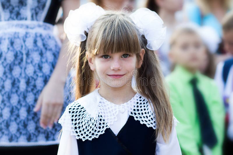 Portrait d'une belle petite fille dans une robe d'école et dans les arcs Première catégorie image stock Portrait d'une belle petite fille dans une robe d'école et dans les arcs Première catégorie image stock