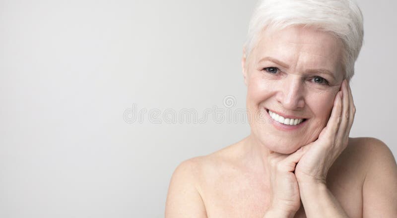 Portrait d'une charmante femme âgée touchant sa peau photographie stock libre de droits