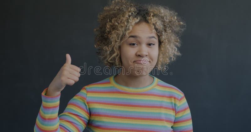 Portrait d'une femme afro-américaine joyeuse montrant un geste de la main de thumbsup sur fond noir banque de vidéos