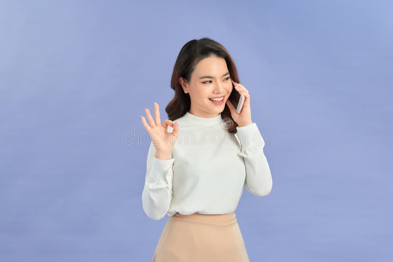 Portrait d'une femme asiatique montrant ok signe et utilisation de téléphone portable recommander application photographie stock libre de droits