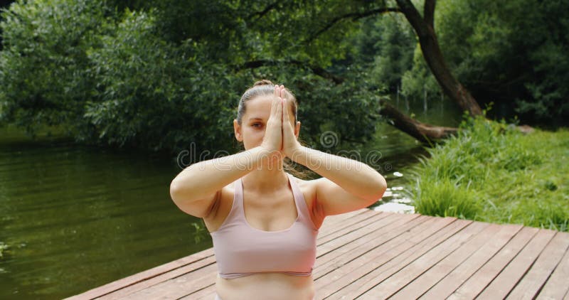 Portrait d'une femme enceinte souriante faisant du yoga prénatal dans le parc près du lac banque de vidéos