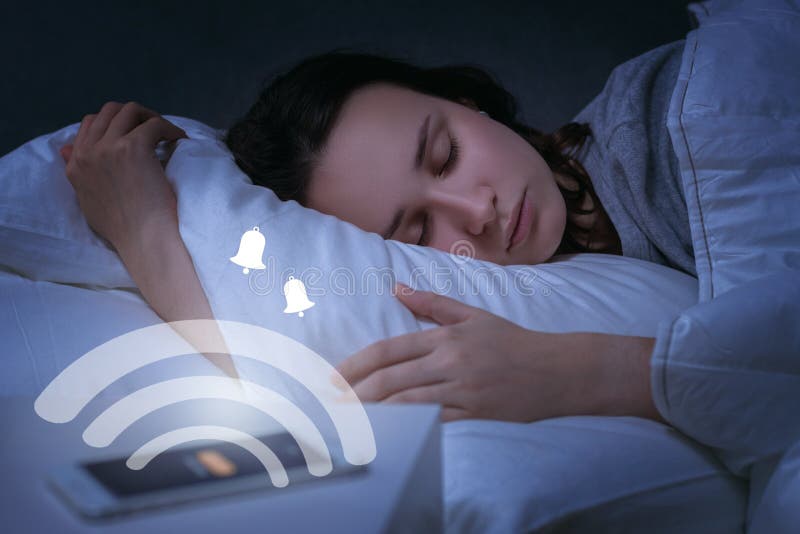 Portrait d'une femme endormie avec smartphone message d'alarme ou signal de rappel à l'écran image tonique avec élément numérique image stock