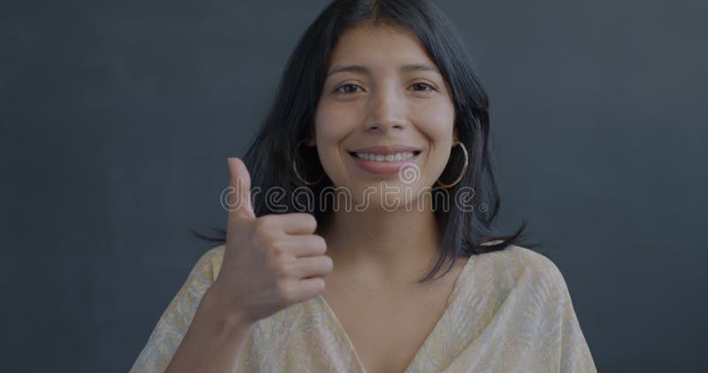 Portrait d'une femme hispanique joyeuse montrant un geste de la main de la vignette souriant sur fond noir banque de vidéos