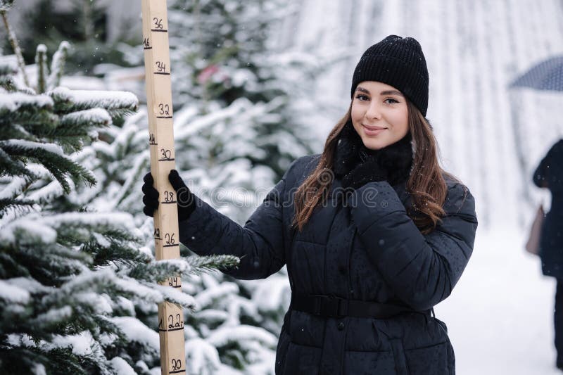 Portrait d'une femme élégante achète un arbre de noël. femme dans un pull tricoté noir. belle dame choisir sapin et photos libres de droits