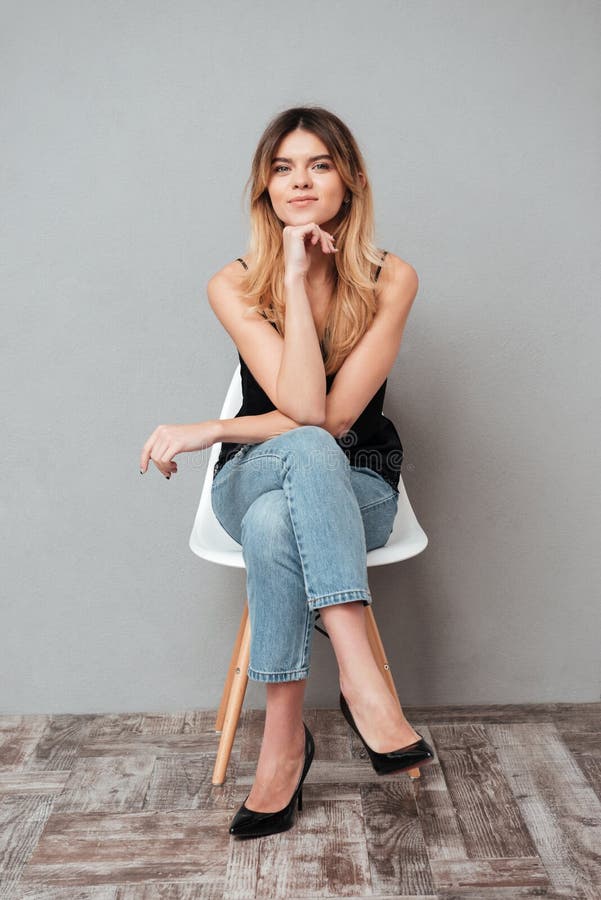 Portrait d'une fille attirante de sourire s'asseyant sur une chaise photos stock Portrait d'une fille attirante de sourire s'asseyant sur une chaise photos stock