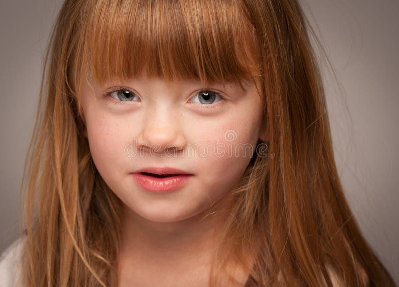 Portrait d'une fille d'une chevelure rouge adorable sur le gris photos stock Portrait d'une fille d'une chevelure rouge adorable sur le gris photos stock