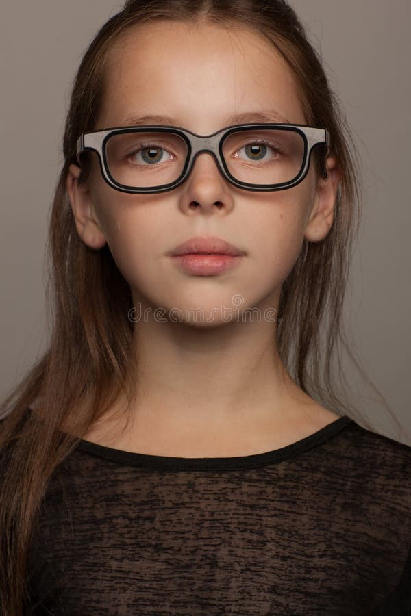 Portrait d'une fille de huit ans avec une humeur calme, en chemisier noir et verres avec la jante noire Séance photo de studio images stock Portrait d'une fille de huit ans avec une humeur calme, en chemisier noir et verres avec la jante noire Séance photo de studio images stock