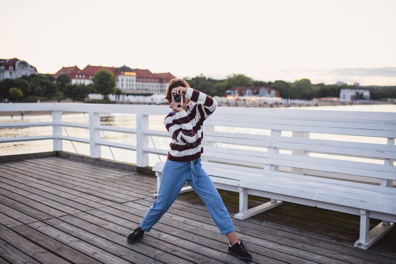 Portrait d'une fille de préadolescence prise de photo avec caméra sur quai par mer au coucher du soleil concept de vacances. images stock