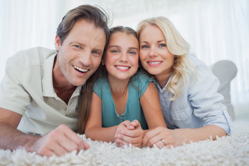 Portrait d'une fille et de ses parents se trouvant sur un tapis images libres de droits