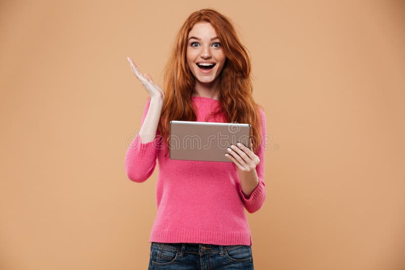 Portrait d'une fille rousse joyeuse heureuse tenant le comprimé photos stock