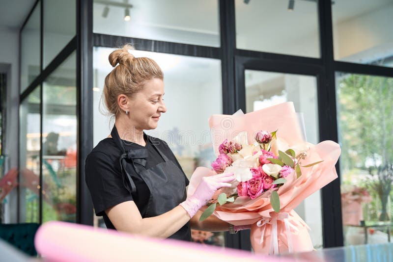 Portrait d'une fleuriste regardant le bouquet dans la boutique de fleurs image stock
