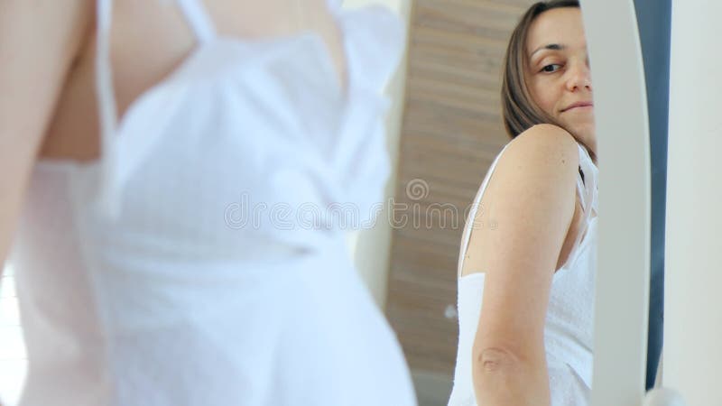 Portrait d'une jeune femme adulte heureuse habillée en tenue de nuit devant un miroir