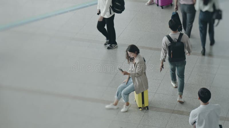 Portrait d'une jeune femme d'affaires assise sur un bagage au coeur du terminal. femme vérifiant le téléphone à l'aéroport en atte