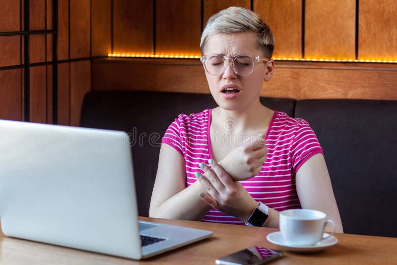 Portrait d'une jeune femme d'affaires malheureuse avec de courts cheveux blonds en t-shirt rose et lunettes assises au café et br photos stock