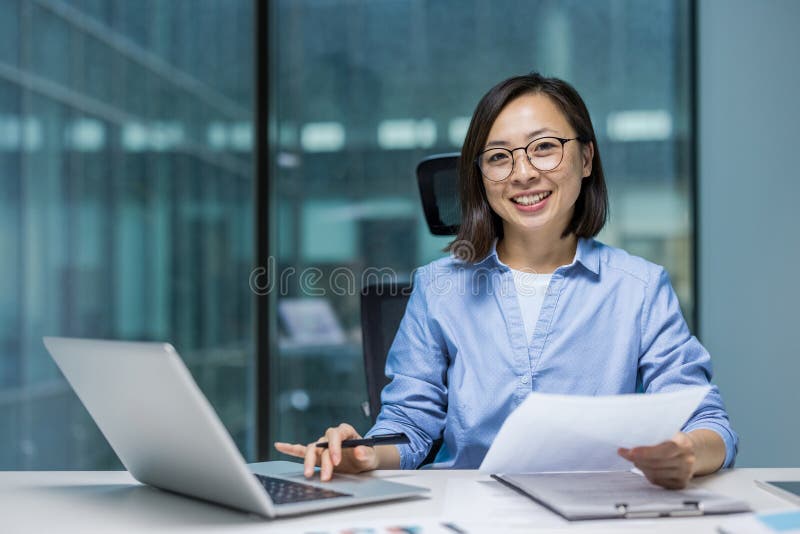 Portrait d'une jeune femme d'affaires qui réussit au bureau. Asiatique derrière la paperasse souriant et regardant photos libres de droits