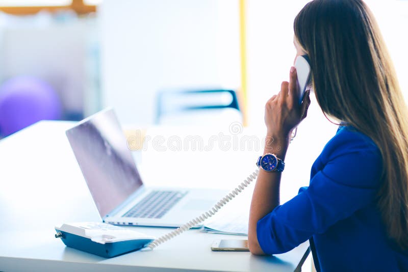 Portrait d'une jeune femme au téléphone devant un ordinateur portable images libres de droits