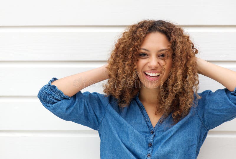 Portrait d'une jeune femme heureuse souriant avec des mains dans les cheveux image stock Portrait d'une jeune femme heureuse souriant avec des mains dans les cheveux image stock