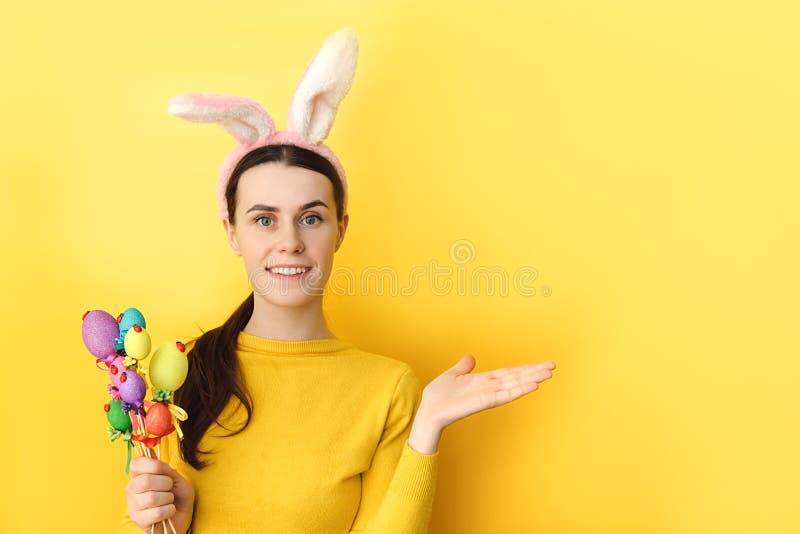 Portrait d'une jeune femme ravie porte des oreilles de lapin lève le palmier comme si montrer quelque chose gestes sur un espace v photographie stock libre de droits