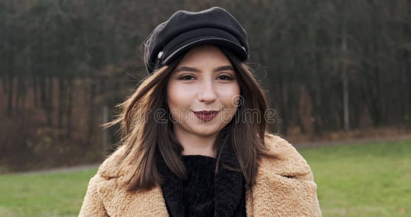 Portrait d'une jeune femme séduisante qui sourit et regarde la caméra sur la pelouse verte Jolie femme avec clips vidéos