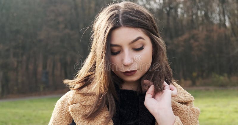 Portrait d'une jeune femme séduisante qui sourit et regarde la caméra sur la pelouse verte Jolie femme Fermer clips vidéos