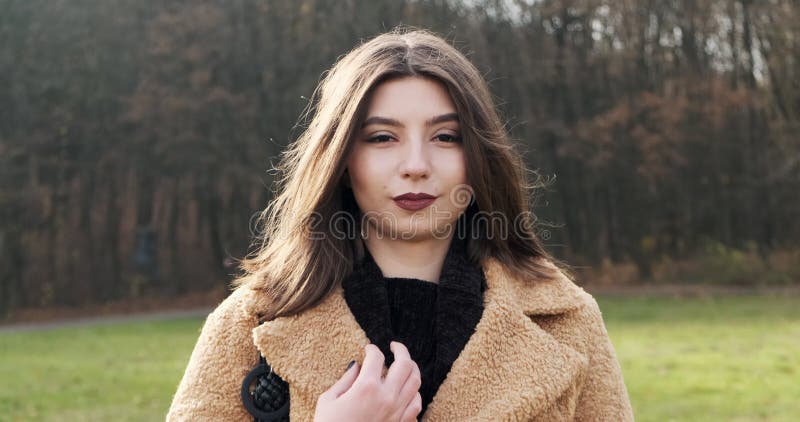 Portrait d'une jeune femme séduisante qui sourit et regarde la caméra sur la pelouse verte Jolie femme Fermer clips vidéos