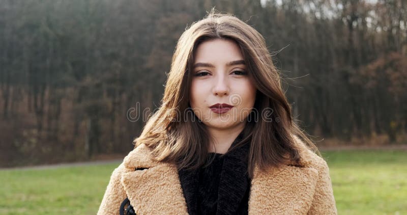 Portrait d'une jeune femme séduisante qui sourit et regarde la caméra sur la pelouse verte Jolie femme Fermer banque de vidéos