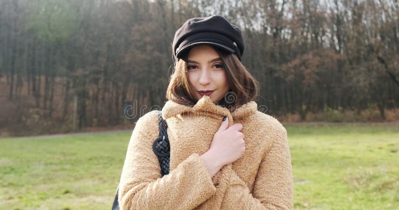 Portrait d'une jeune femme séduisante qui sourit et regarde la caméra sur la pelouse verte Jolie femme se cache clips vidéos