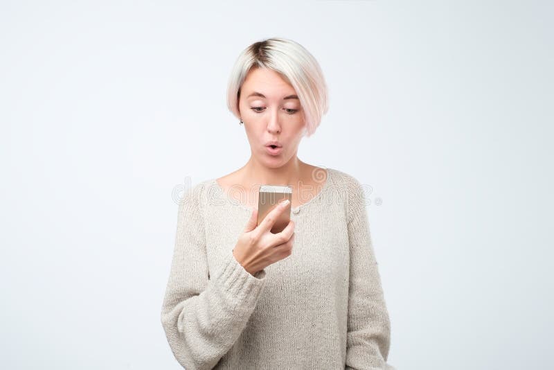 Portrait d'une jeune fille choquée regardant l'écran de téléphone portable dans des sms de lecture de surprise image stock Portrait d'une jeune fille choquée regardant l'écran de téléphone portable dans des sms de lecture de surprise image stock